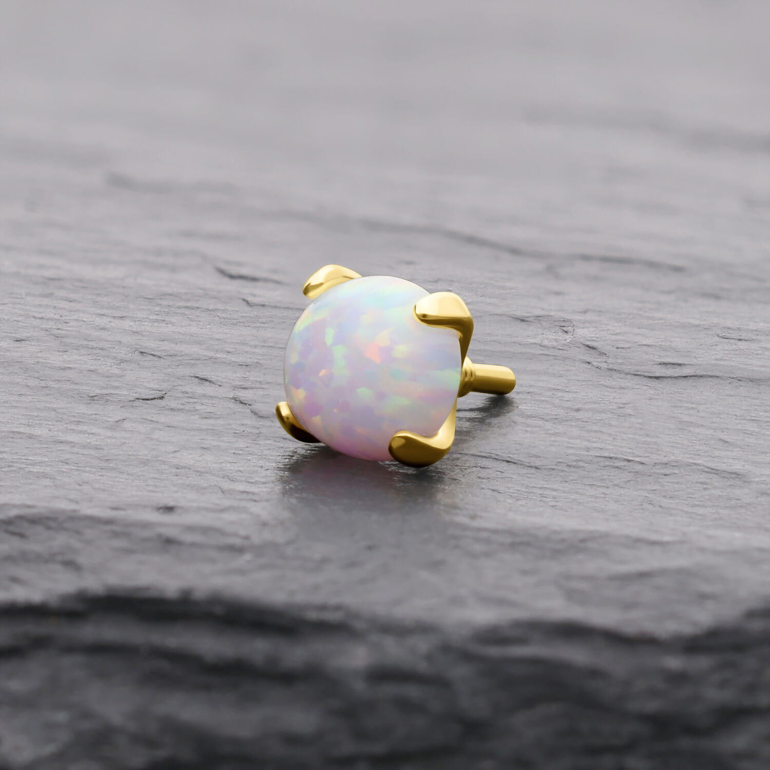 Runder 14K Goldaufsatz mit synthetischem Opal auf grauem Hintergrund