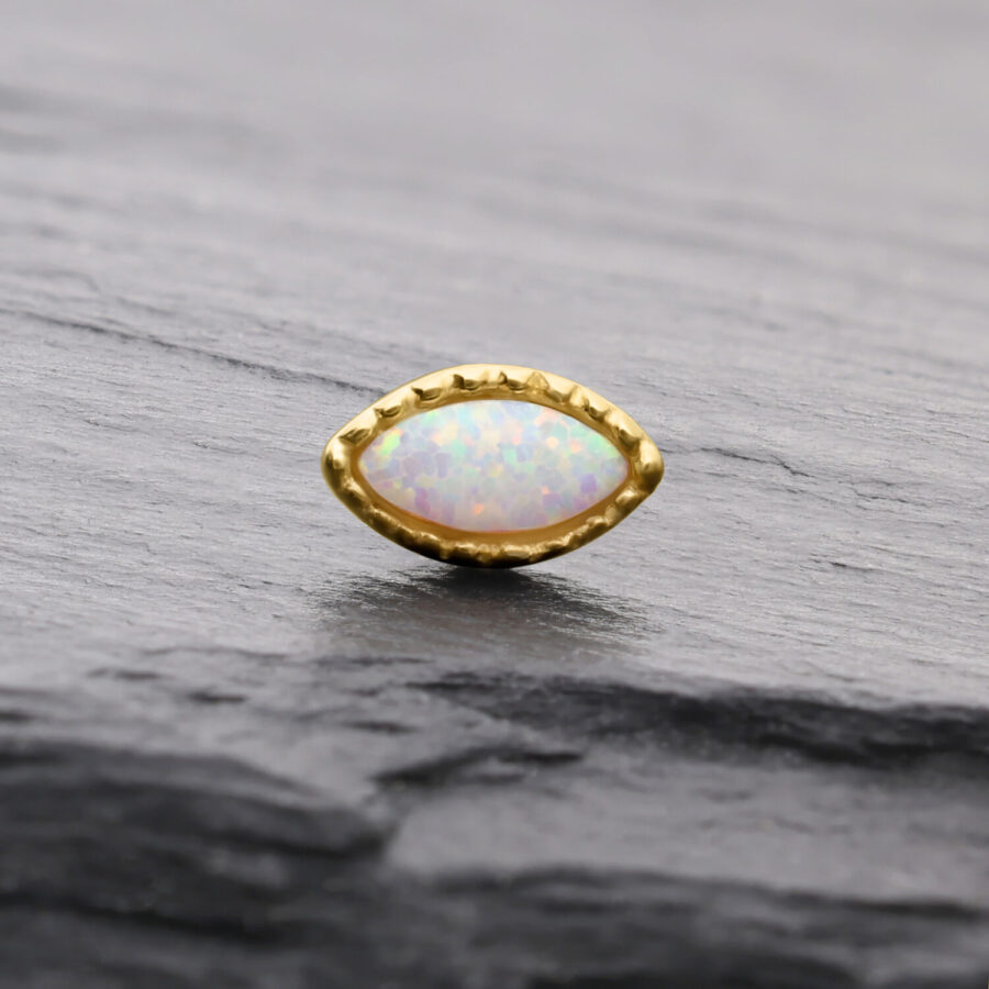 Ovaler synthetischer Opal in goldener Fassung auf grauem Hintergrund