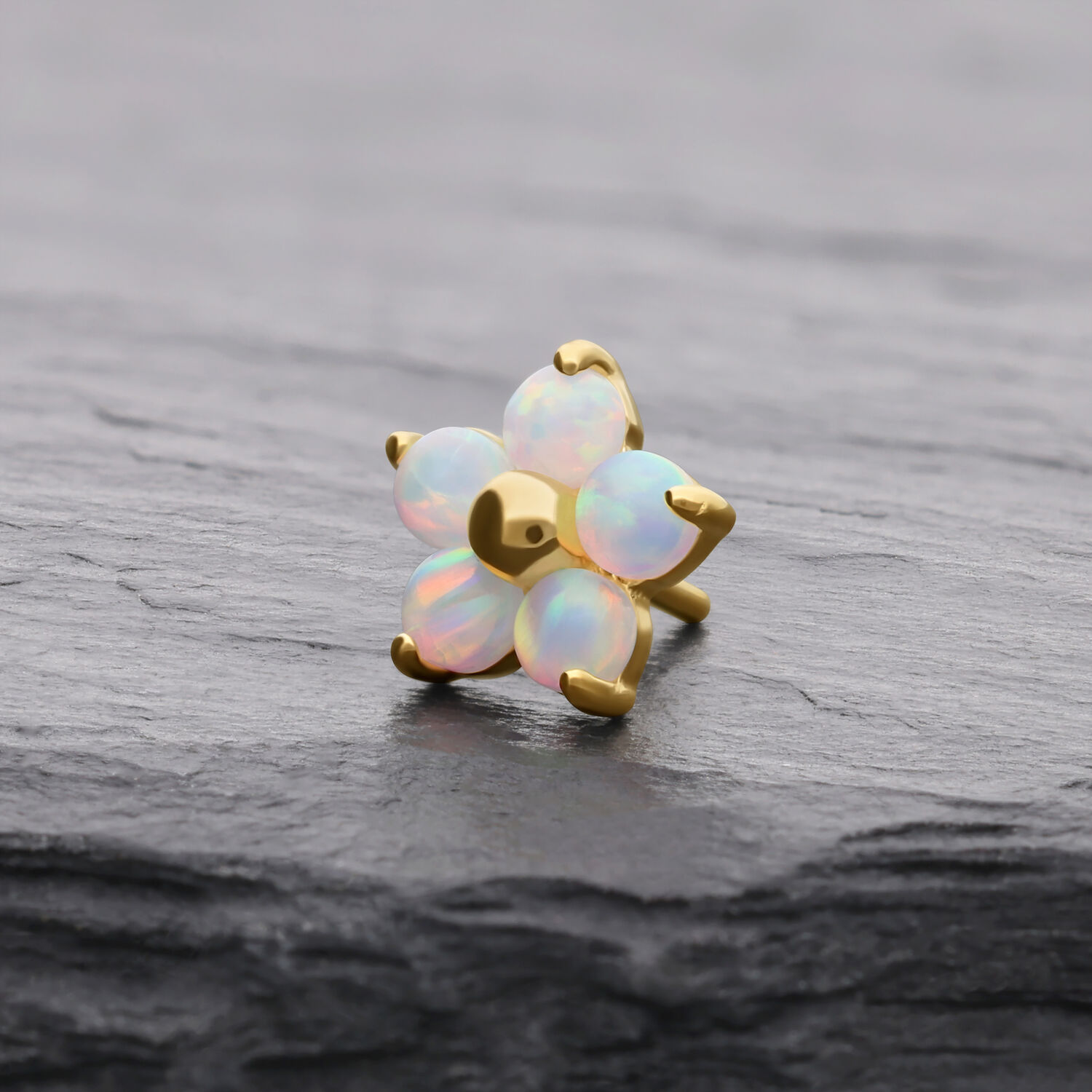 Goldener Blume-Aufsatz mit synthetischem Opal auf grauem Hintergrund
