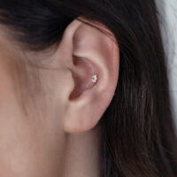 Nahaufnahme eines Ohres mit einem 14K Gold Blume Opal Aufsatz
