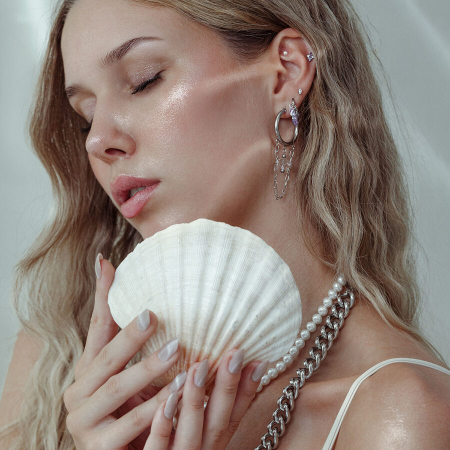 Frau mit Piercing-Aufsatz und Muschel, Ohrringe aus Silber und Gold