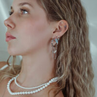 Eleganter Ohrschmuck mit Kristallen in Silber Frau mit silbernen Ohrpiercings und Kristallen, Nahaufnahme