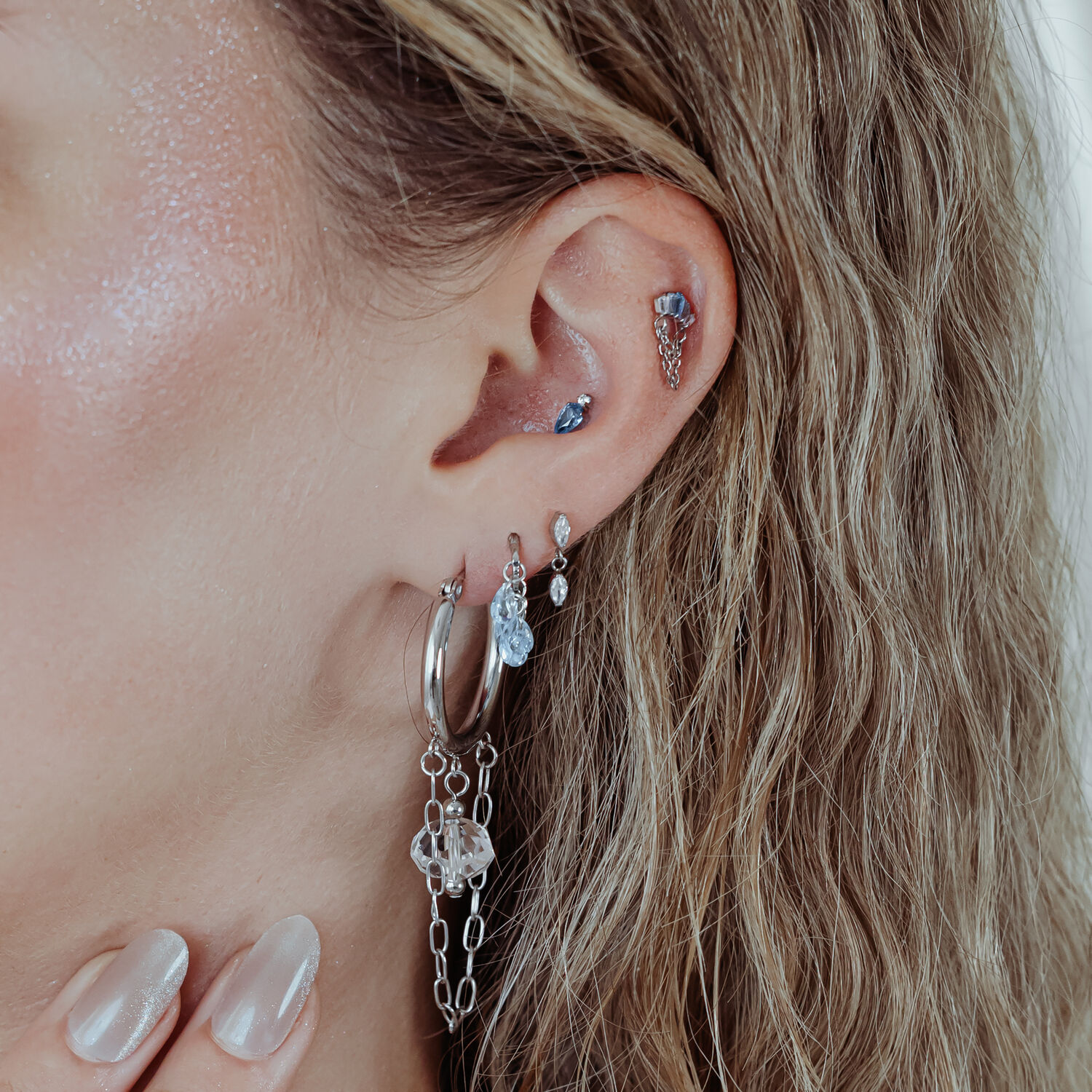 Mystic Dew Ohrpiercing in Silber und Gold Ohr mit mehreren Piercings, darunter ein silbernes Mystic Dew Aufsatz