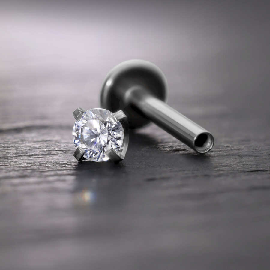 Silberner Prong Aufsatz mit Kristall für Innengewinde Labret auf grauem Hintergrund