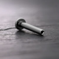 Silbernes Titan Push Fit Labret auf dunklem Holzuntergrund