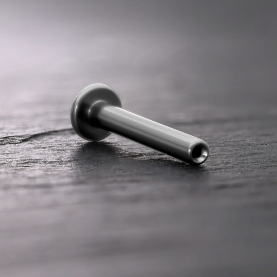 Silbernes Titan Push Fit Labret auf dunklem Holzuntergrund