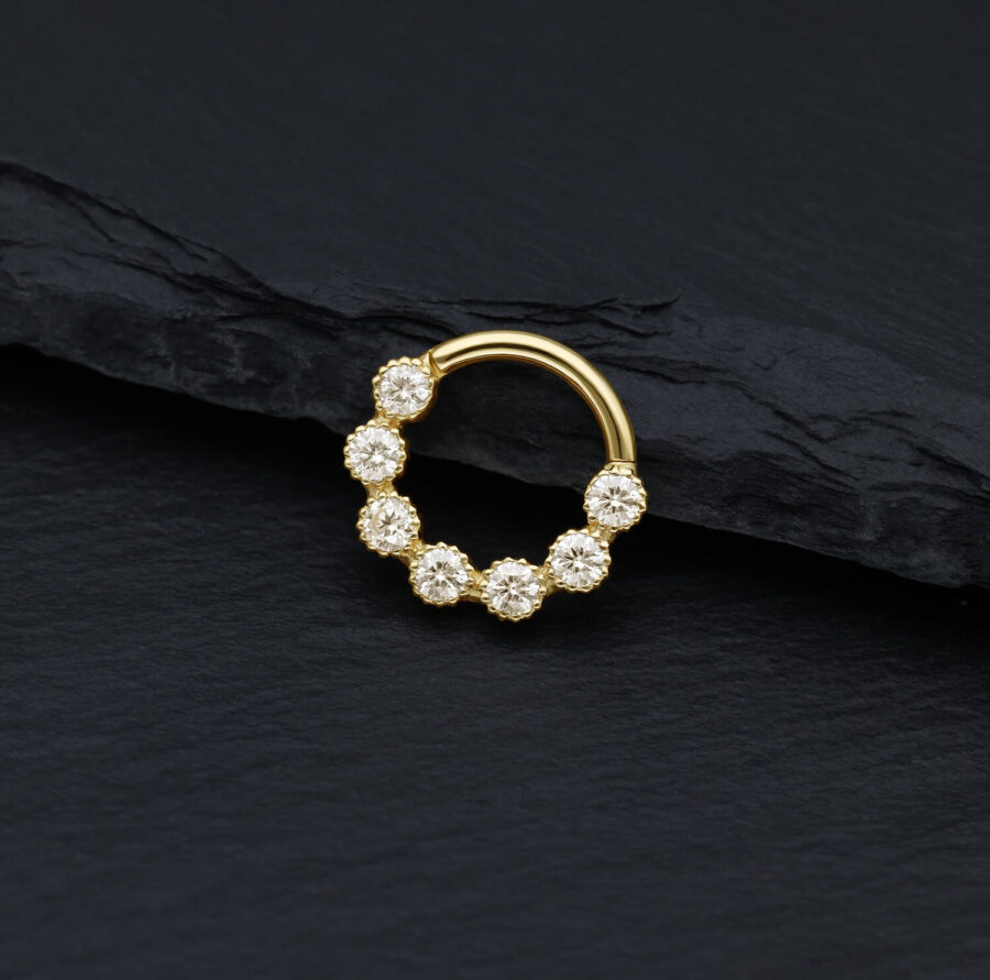 Goldener Piercingring mit funkelnden Moissanit Steinen auf schwarzem Hintergrund