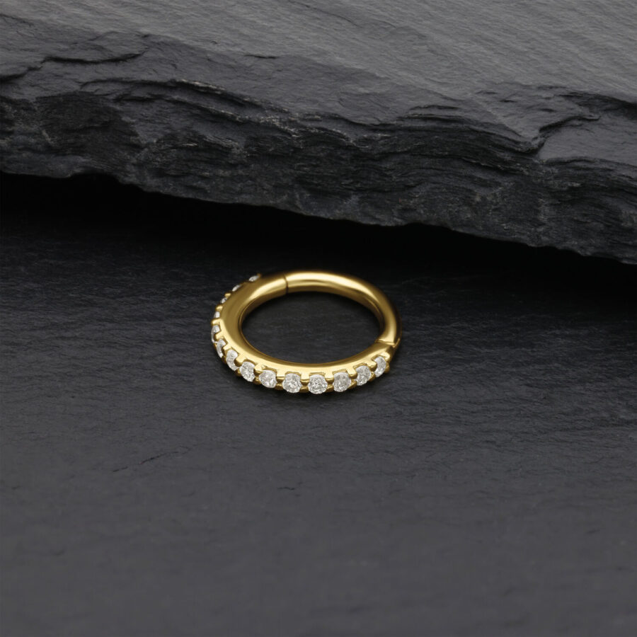 Goldener Nasenring mit Moissanit Kristallen auf schwarzem Stein