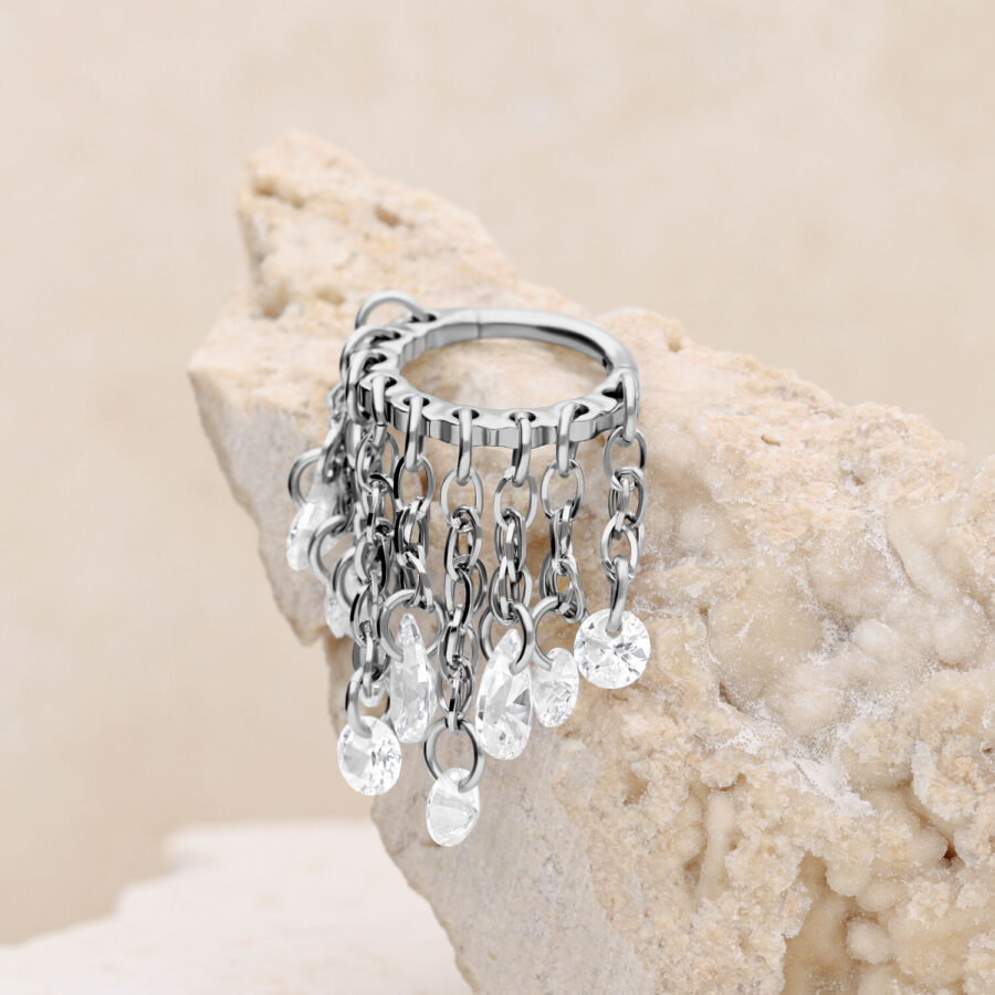 Silberner Piercingring mit klaren Kristallen auf hellem Stein