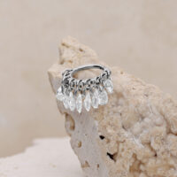 Silberner Clicker mit klaren Kristallen Silberner Piercing-Ring mit klaren Kristallen auf beigem Hintergrund