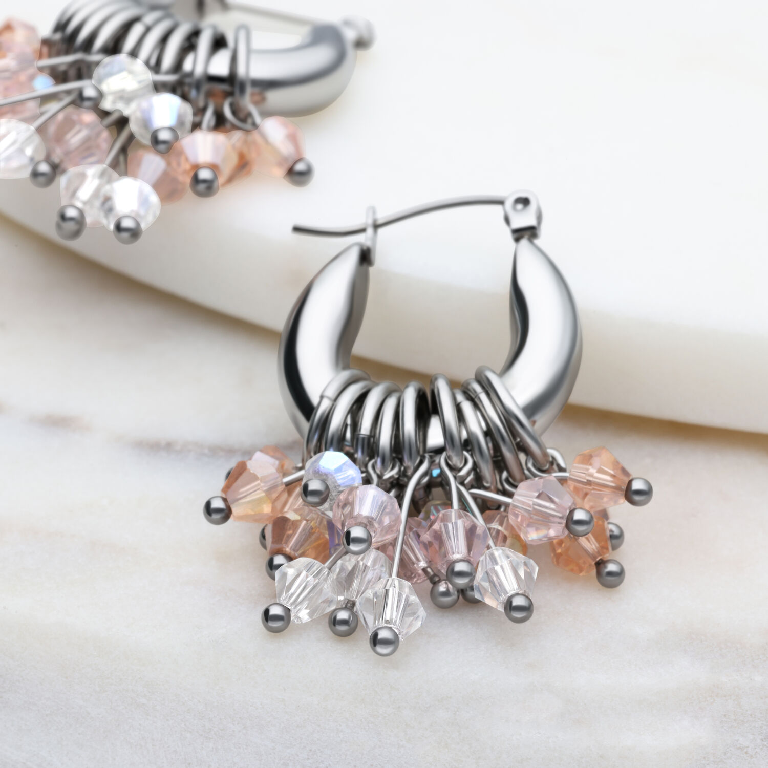 Silberne Glamour Hoops Ohrringe mit bunten Kristallen auf marmoriertem Hintergrund