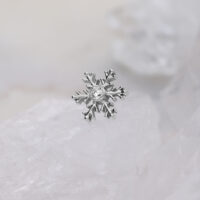 Schneeflocken-Aufsatz aus Titan mit Kristall Silberner Schneeflocken-Piercingaufsatz mit klarem Kristall auf weißem Hintergrund
