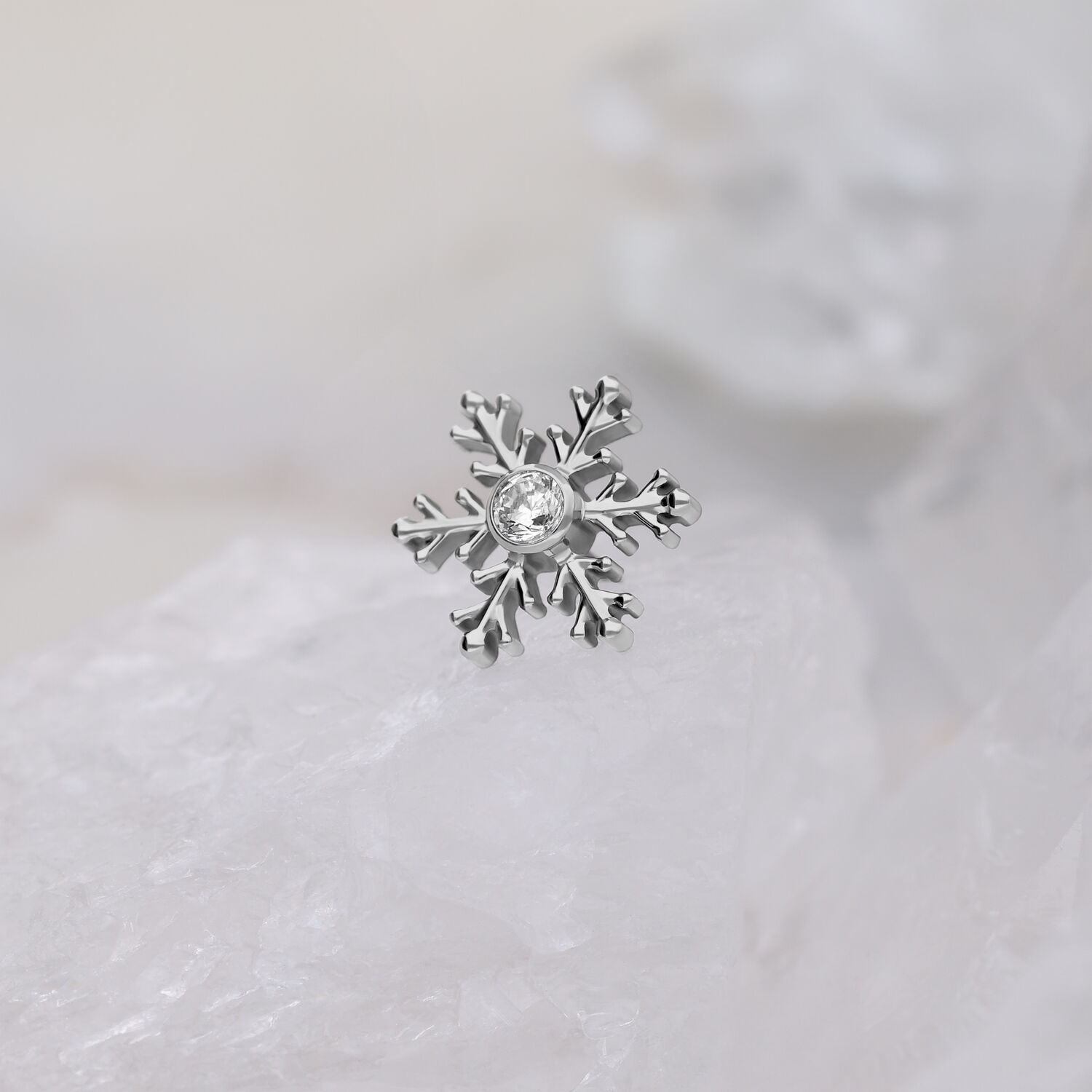 Schneeflocken-Aufsatz aus Titan mit Kristall Silberner Schneeflocken-Piercingaufsatz mit klarem Kristall auf weißem Hintergrund