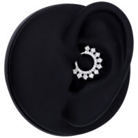 Silberner Kristall Septum Clicker an einem schwarzen Modell-Ohr auf weißem Hintergrund