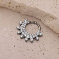 Silberner Septum Clicker mit Kristallen Silberner Septum Clicker mit funkelnden Kristallen auf beigem Hintergrund