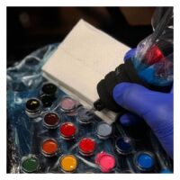 Weiße Tattoo-Handtücher neben Tattoo-Farben und Handschuhen
