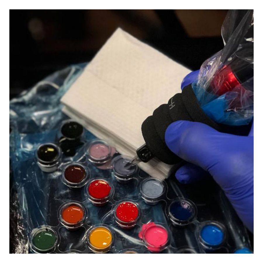 Weiße Tattoo-Handtücher neben Tattoo-Farben und Handschuhen