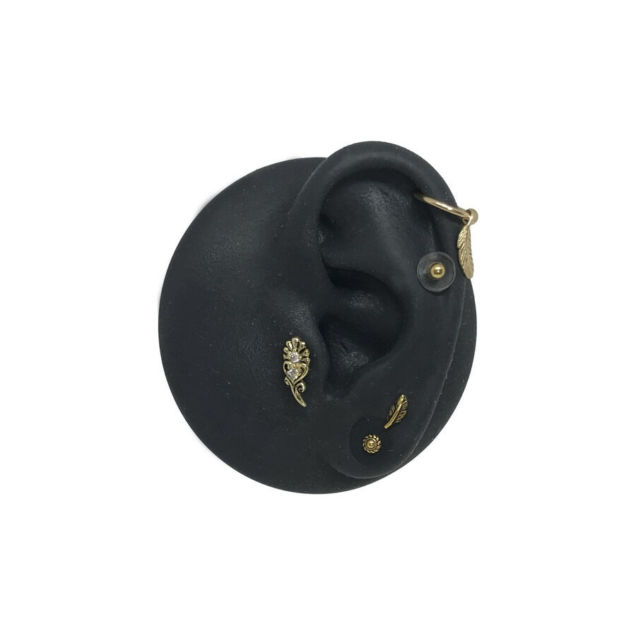Silikon Disc für Piercing mit goldenen Aufsätzen Schwarzes Silikon-Ohrenmodell mit goldenen Piercing-Aufsätzen auf weißem Hintergrund