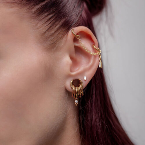 Ohr mit mehreren goldenen Piercings und einer Kette, Nahaufnahme