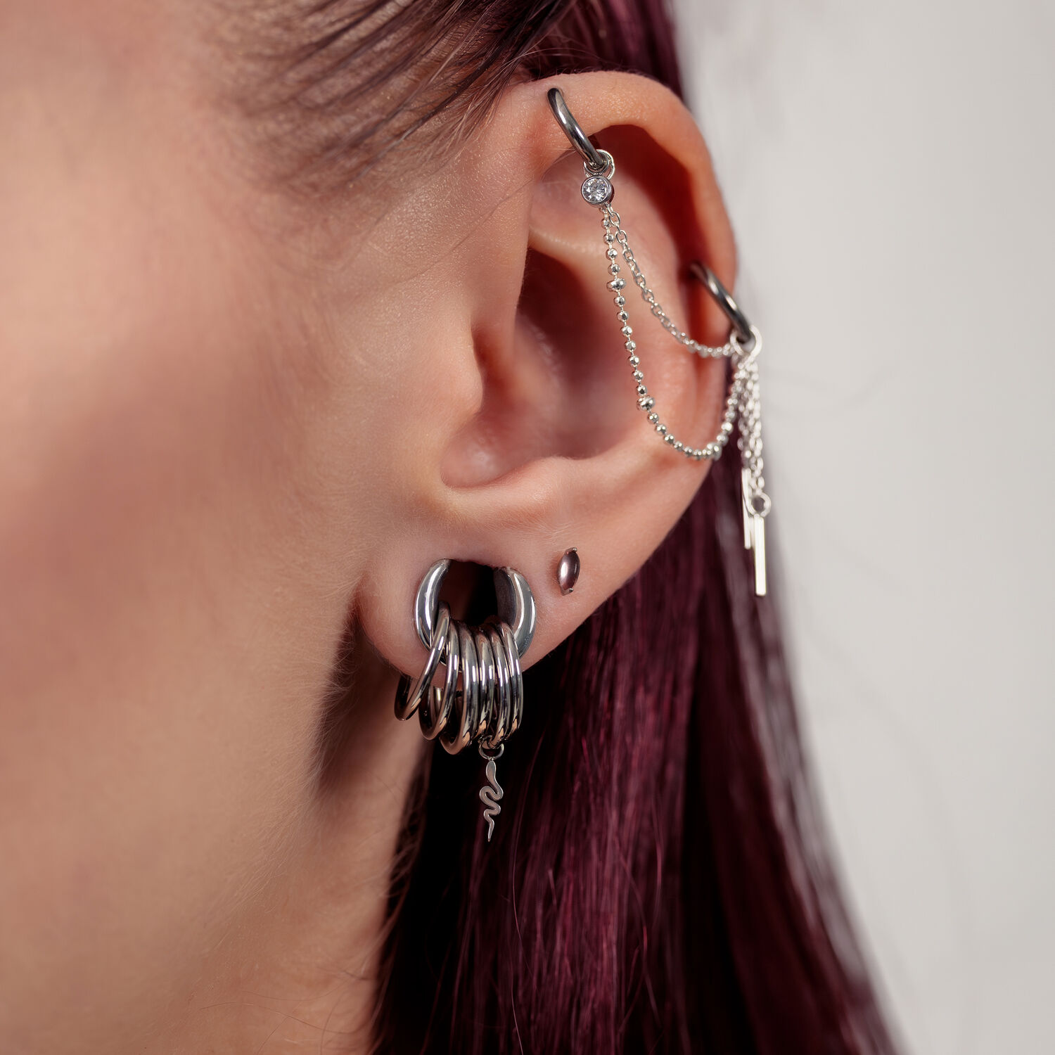 Silberne Push Fit Aufsätze mit Amethyst Nahaufnahme eines Ohres mit silbernen Piercingaufsätzen und Ketten