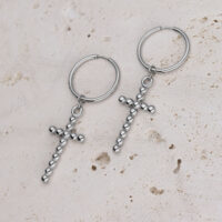 Silberne Bubble Cross Hoops Ohrringe Zwei silberne Creolen mit Kreuzanhängern auf hellem Stein