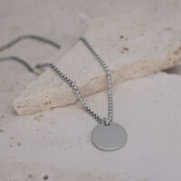 Silberne Kette mit rundem Anhänger Silberne Kette mit rundem Anhänger auf hellem Steinboden