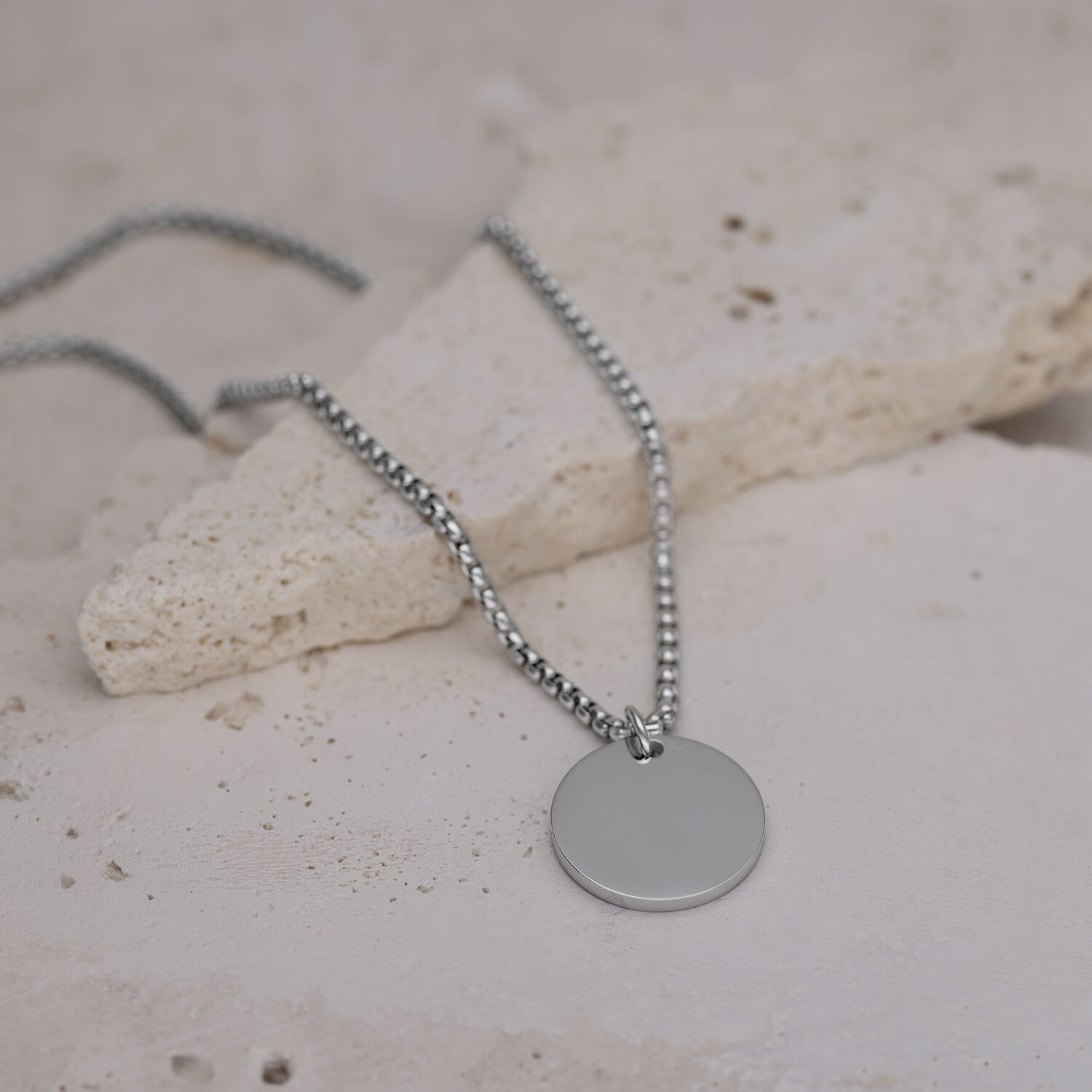 Silberne Kette mit rundem Anhänger Silberne Kette mit rundem Anhänger auf hellem Steinboden