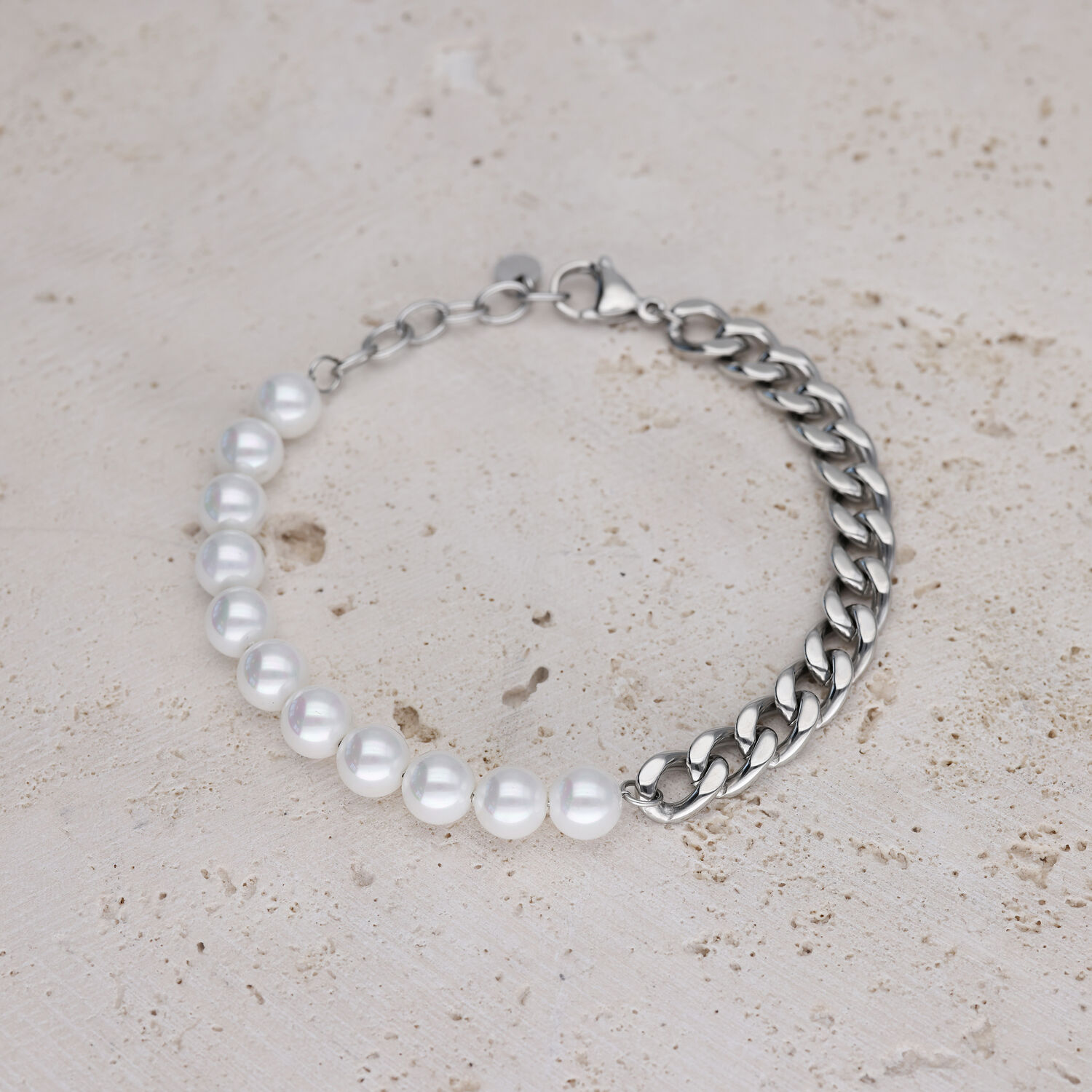Armband mit weißen Perlen und silberner Kette auf hellem Stein
