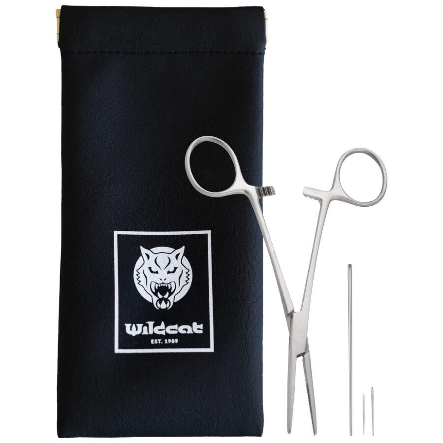Silberne Piercingzange und Nadeln neben schwarzer Tasche mit Wildcat-Logo