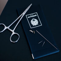 Piercing Wechselset mit Werkzeug Piercing-Set mit Zange, Nadeln und Kleinteilen auf schwarzem Hintergrund