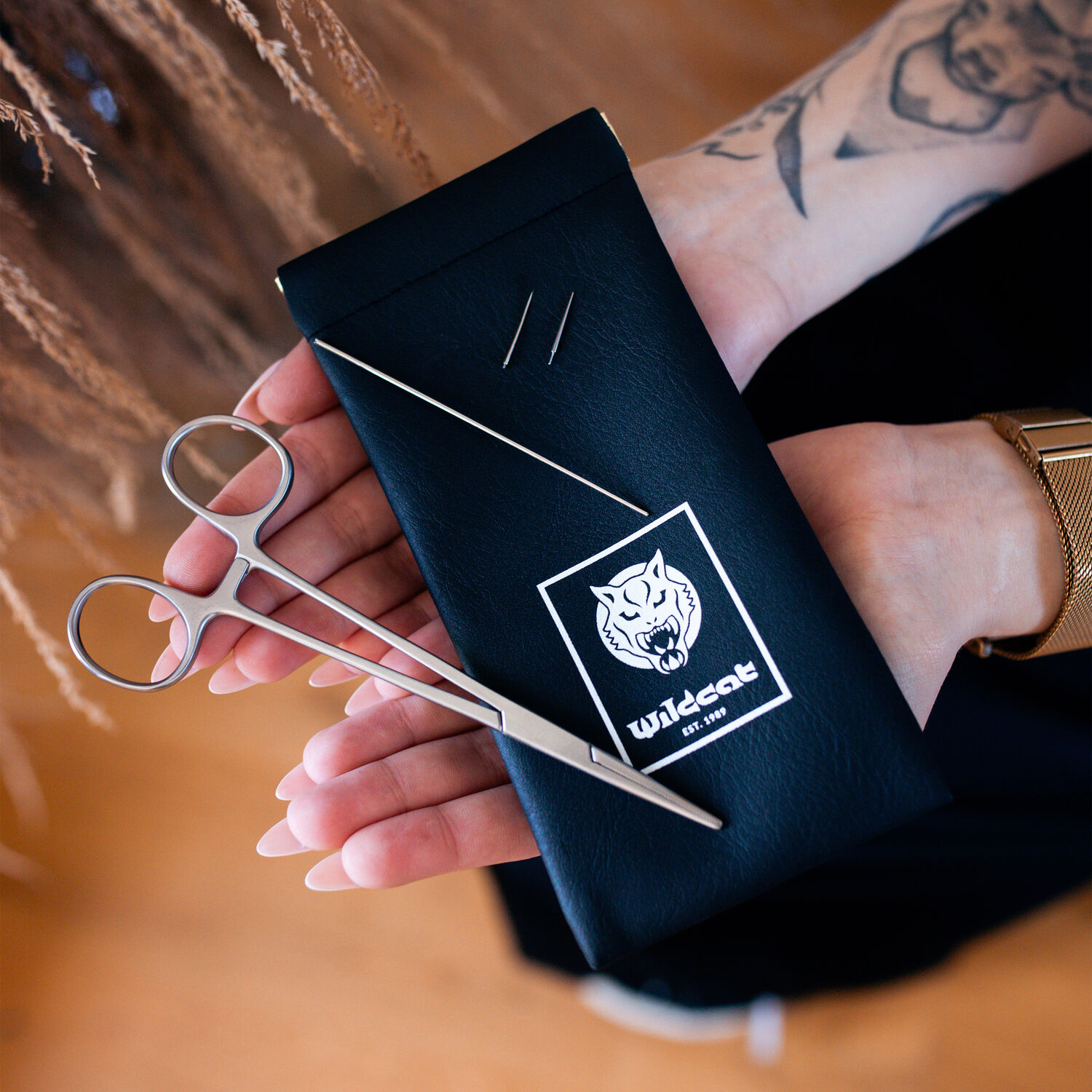 Piercing Wechselset mit Schere und Nadel Schwarzes Etui mit Wildcat-Logo, zwei Nadeln und Schere, auf Händen gehalten