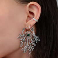 Nahaufnahme eines Ohres mit silbernem Ohrhänger in Blumenform und kleinem Stecker