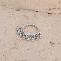Silberner Titan Septum Clicker mit Kugeln Silberner Septum Clicker mit kleinen Kugeln auf einem strukturierten Steinuntergrund
