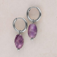 Silberne Creolen mit Amethystanhänger Zwei silberne Creolen mit violettem Amethystanhänger auf beigem Hintergrund