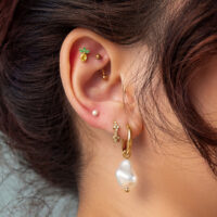 Ohrenpiercing mit goldenem Ananas-Aufsatz und Perlenanhänger