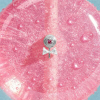 Silberner Lollipop Piercing Aufsatz Silberner Lollipop-Aufsatz mit pinkem Stein auf glitzerndem pinken Hintergrund