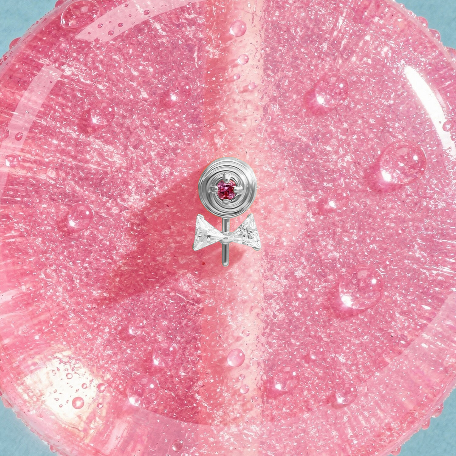 Silberner Lollipop Piercing Aufsatz Silberner Lollipop-Aufsatz mit pinkem Stein auf glitzerndem pinken Hintergrund