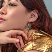 Silberne Ohrringe und Piercings Frau mit mehreren silbernen Ohrringen und Piercings, goldene Kleidung