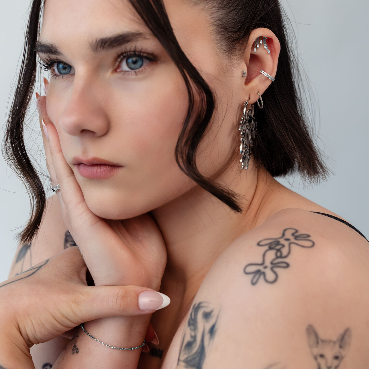 Silberner Helix Aufsatz mit Oval Drop Design Frau mit mehreren Ohrpiercings, darunter ein silberner Helix Aufsatz, Nahaufnahme