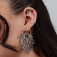 Silberne Helix Ohr-Piercing Aufsätze Nahaufnahme eines Ohres mit mehreren silbernen Piercings, darunter ein großer ovaler Anhänger und funkelnde Steckaufsätze.