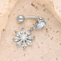 Silbernes Blüten-Bauchnabelpiercing mit Kristall Silbernes Bananabell-Piercing mit blütenförmigem Kristallanhänger auf sandfarbenem Hintergrund