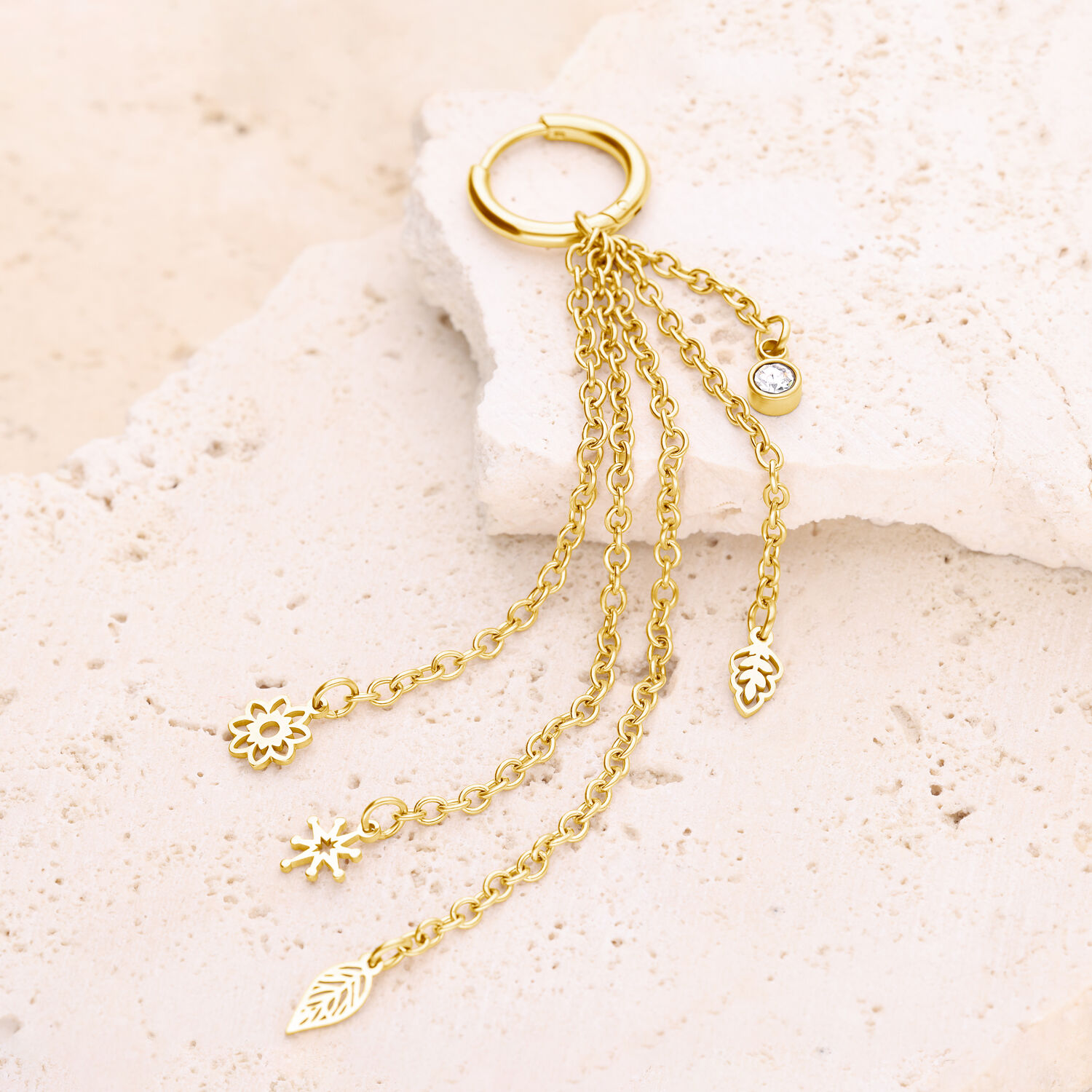Goldene Boho Ohrhänger mit Anhängern Goldene Ohrringe mit vier baumelnden Anhängern auf hellem Stein