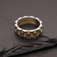 Silberner und goldener Ring aus Chirurgenstahl auf dunklem Stein