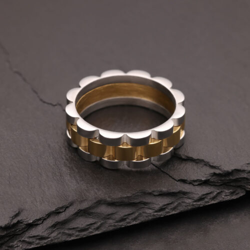 Silberner und goldener Ring aus Chirurgenstahl auf dunklem Stein