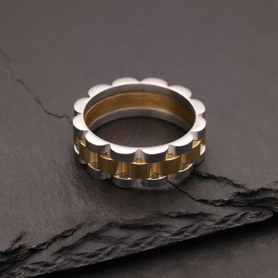 Silberner und goldener Ring aus Chirurgenstahl auf dunklem Stein