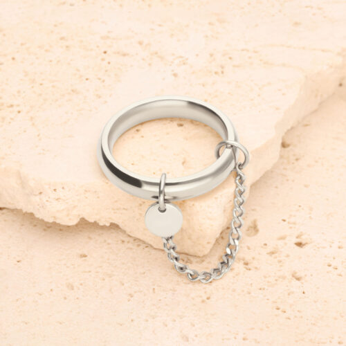 Silberner Ring mit kleiner Kette und rundem Anhänger auf hellem Stein