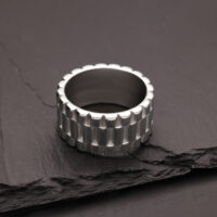 Silberner Ring mit geriffelter Oberfläche auf dunklem Schiefer