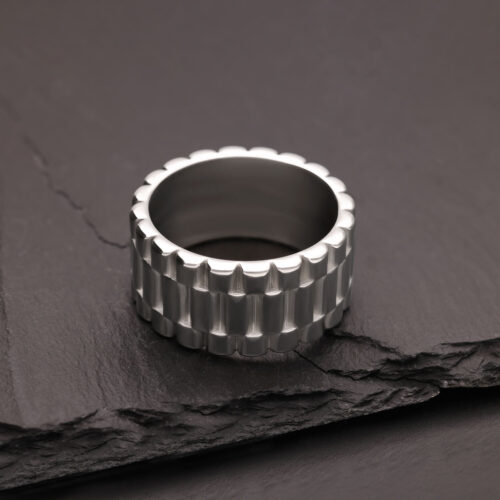 Silberner Ring mit geriffelter Oberfläche auf dunklem Schiefer