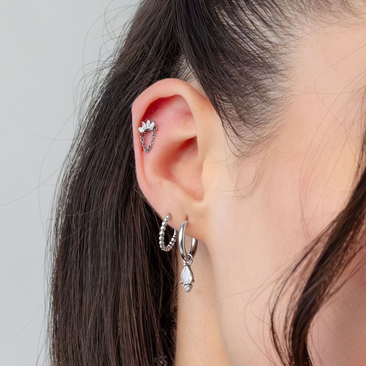 Silberner Kristall-Kronen-Piercingaufsatz Ohr mit mehreren silbernen Piercings, darunter ein kristallklarer Kronenaufsatz