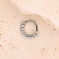Silberner Piercingring mit Kristallen auf heller Steinoberfläche